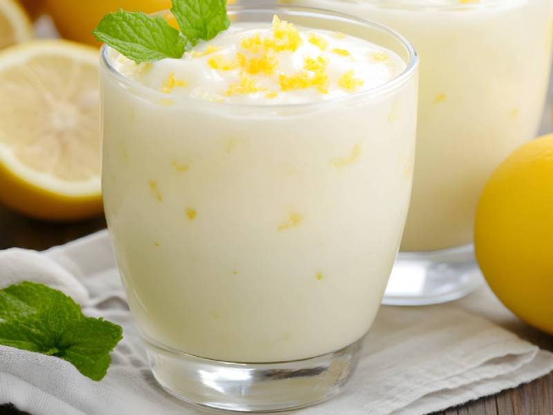 Dos vasos de quark de limón sobre una mesa, con limones al lado